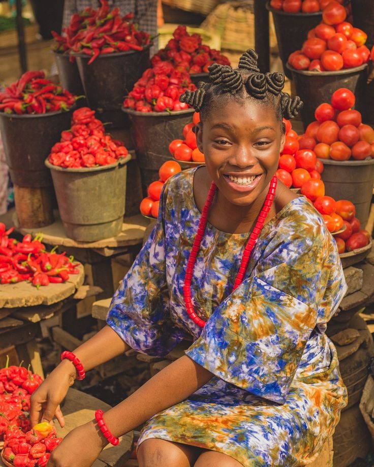 A smiling African market trader surrounded by fresh produce at her stall